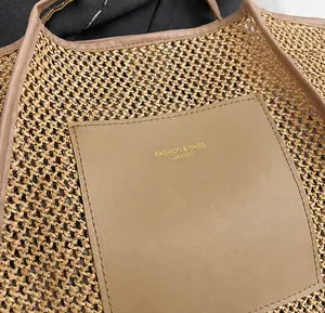 Detailaufnahme der gewebten Strohtasche mit brauner Ledertasche und goldener Aufschrift