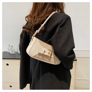 Close-up of minimalist cream underarm bag with gold buckle and adjustable strap