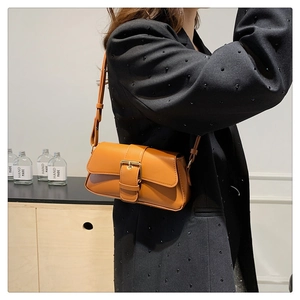 Detailed shot of a brown crossbody bag with gold buckle on a tailored black blazer