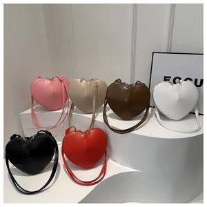 Detailed view of heart-shaped leather crossbody bags in six vibrant colors on white display