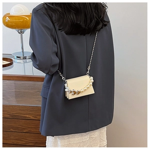 Vue arrière détaillée d'un mini sac beige à chaîne avec perles et détails métal en cœur
