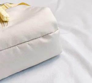 Primer plano de la tela de nailon beige de la riñonera con detalles tejidos amarillos