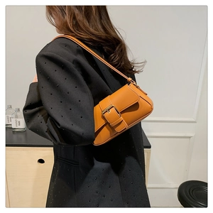Brown orange baguette bag with large metal buckle worn as a shoulder underarm bag