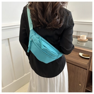 Détail du sac bandoulière vert en nylon avec double fermeture éclair et cordons