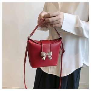 Close-up of red leather bucket bag featuring a silver bow buckle and adjustable strap