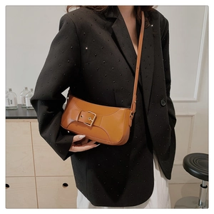 Brown leather underarm bag with large gold buckle on model with black beaded blazer