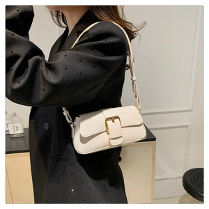 Detail view of cream white crossbody bag with gold buckle and adjustable strap