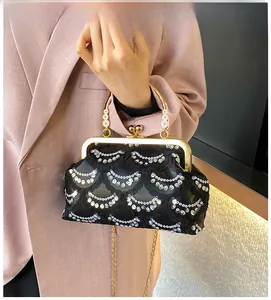 Dettaglio borsa da sera con paillettes nere con cornice dorata e manico di perle