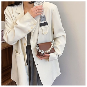 Détail d'un mini sac bandoulière marron avec chaîne en perles et pendentif coeur argenté