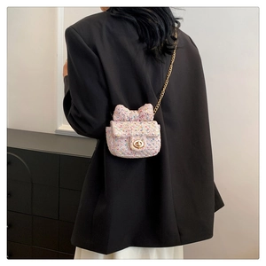 Pink tweed mini crossbody bag with a large bow and gold chain on black blazer