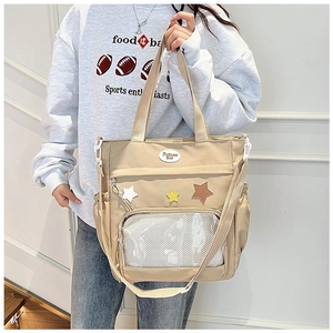 Detail der beigen Nylon-Tragetasche mit Sternen-Patches und transparenter Netztasche