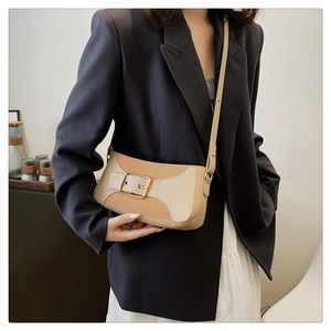 Detail of elegant two-tone beige leather crossbody bag with golden square buckle accessory