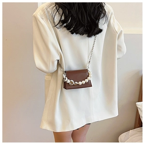 Détail du mini sac bandoulière avec chaîne en perles et cœurs sur un blazer blanc