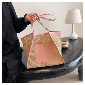 Detail der handgewebten Strohtasche mit rosa Lederbesatz und modischem Schriftzug