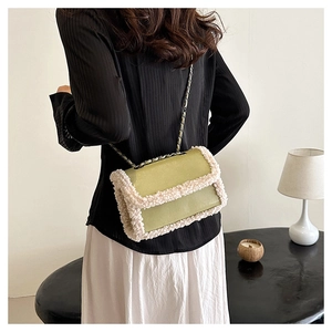Detail van groene lederen crossbodytas met witte bontrand en kettingriem op het model