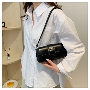 Close-up of black leather shoulder bag with large gold buckle and rectangular flap cover