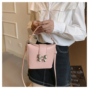 Detail of pink bucket bag with silver butterfly buckle shown on a model