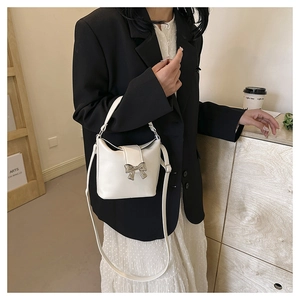 Chic white bucket bag with silver butterfly buckle shown in an elegant lifestyle setting