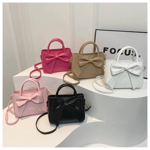 Bow-knot crossbody bags in five colors displayed on minimalist white platforms