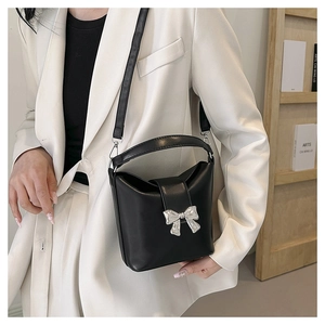 Close-up of black matte bucket bag with a polished silver metallic butterfly bow detail