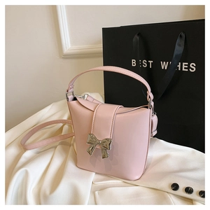 Detail of light pink leather bucket bag featuring silver butterfly metal ornament and strap