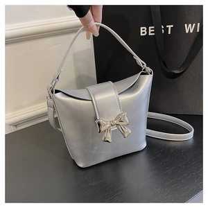 Detail of silver bucket bag with metallic bow and detachable strap for cross-body wear