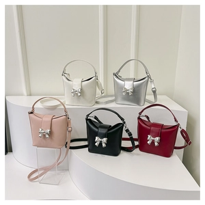 Detail of five stylish crossbody bucket bags with metallic butterfly bow decorations