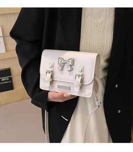 Close-up of cream crossbody bag featuring mirror bow metal and silver buckle details