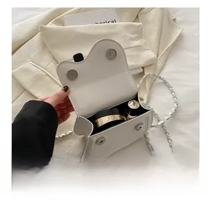 Internal capacity of white saddle bag showing space for cosmetics and leather chain strap