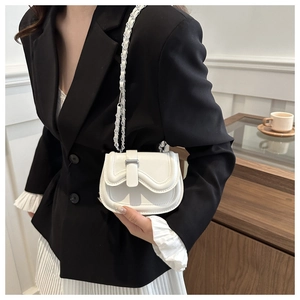 On-model shot of a white mini leather saddle bag with silver chain strap and metal lock