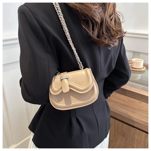 Close-up of mini khaki saddle bag with stylish wave flap and silver chain strap