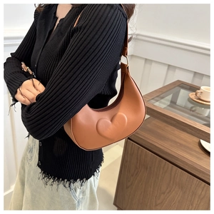 Détail du sac de selle marron avec relief en cœur sur cuir lisse élégant