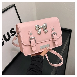 Close-up of pink bow crossbody bag featuring silver buckle detail and leather shoulder strap