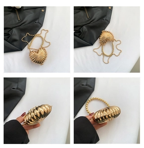 Détail du sac de soirée doré en forme de cœur avec texture coquille et chaîne perlée