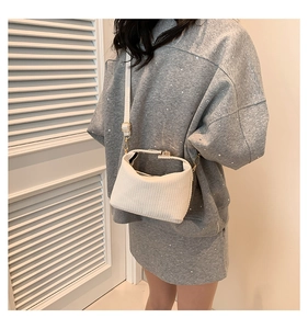 Détail du sac bandoulière blanc avec tissu à rayures verticales et boucle dorée