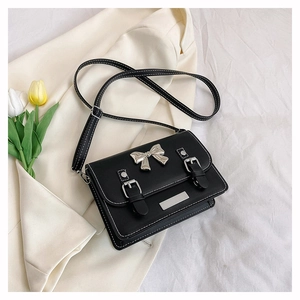 Close-up of black crossbody bag with silver bow accent and white contrast stitching detail