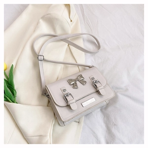 Detail of off-white PU leather small square bag with silver bow and buckle accents