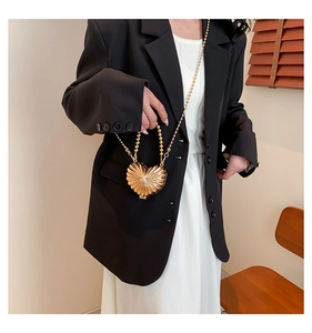 Vue détaillée du mini sac cœur en métal doré avec texture plissée et bandoulière en perles