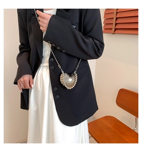 Mini sac cœur argenté avec finition métallique texturée et chaîne perlée porté par un modèle