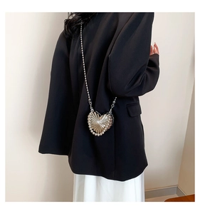 Détail du mini sac cœur argenté avec bordure en perles et bandoulière sur un modèle