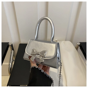 Detail of silver crossbody bag with metallic bow buckle and leather texture