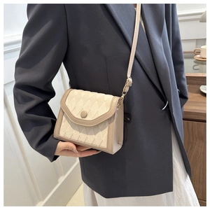 Détail du sac à bandoulière matelassé beige avec surpiqûres et boucle ronde élégante