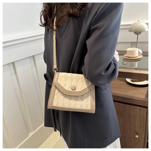 Sac bandoulière matelassé beige et marron clair porté par un mannequin en intérieur