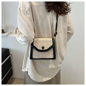 Détail du sac beige matelassé avec bordure en cuir noir et boucle en métal doré