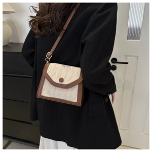 Sac bandoulière matelassé avec bordure en cuir marron porté à l'épaule chez soi