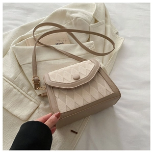 Gros plan sur un sac bandoulière en similicuir matelassé beige sur un blazer beige