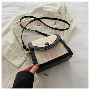 Détail du sac bandoulière beige matelassé avec bordure en cuir noir et boucle ronde