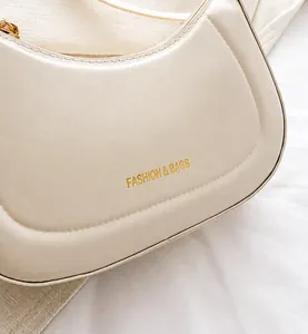 Detail of creamy white faux leather shoulder bag with gold 'Fashion & Bags' lettering