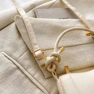 Detail of adjustable shoulder strap with gold metal buckle on cream faux leather bag