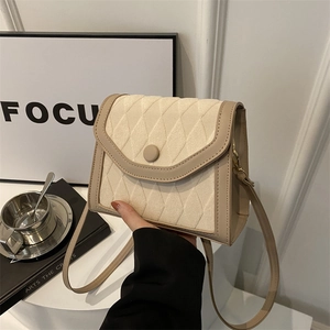 Sac bandoulière matelassé beige et marron avec sangle réglable tenu par un mannequin chic